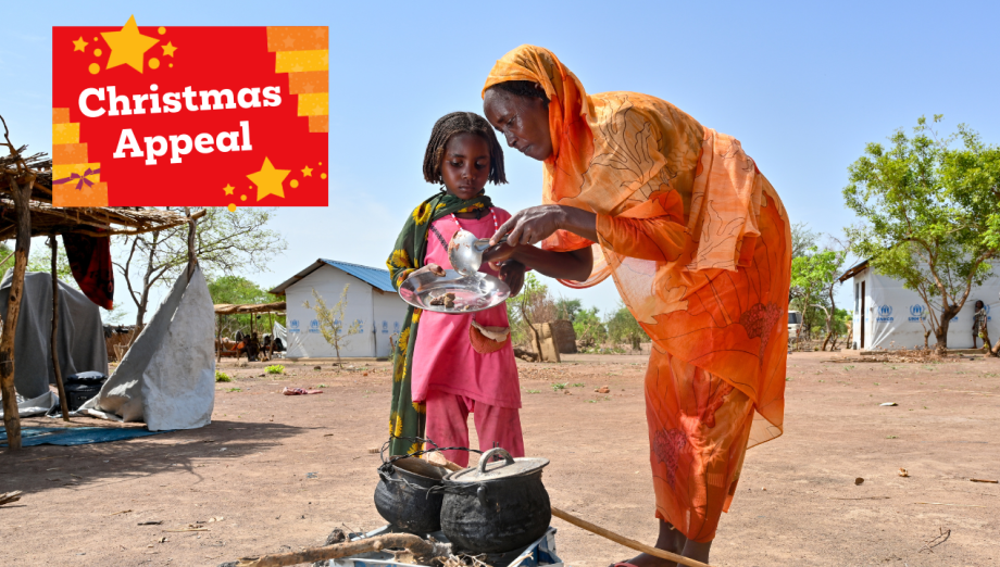 Shede and her daughter gathered around a pot of food. Shede is serving a plate to her daughter.