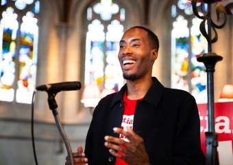 Man wearing a Christian Aid speaker giving a talk at the front a church