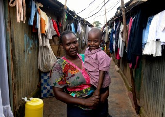  Fridah and her Grandson Quillan outside their home